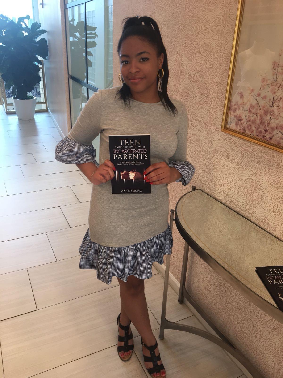 Anyé Young holding a copy of her book Teen Guide to Living With Incarcerated Parents