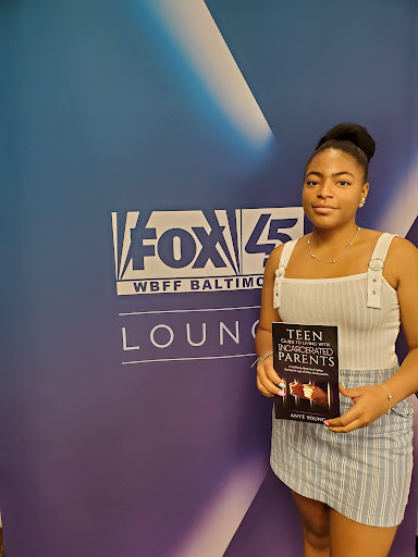 Anyé Young holding her book at the FOX 45 WBFF Baltimore studio lounge